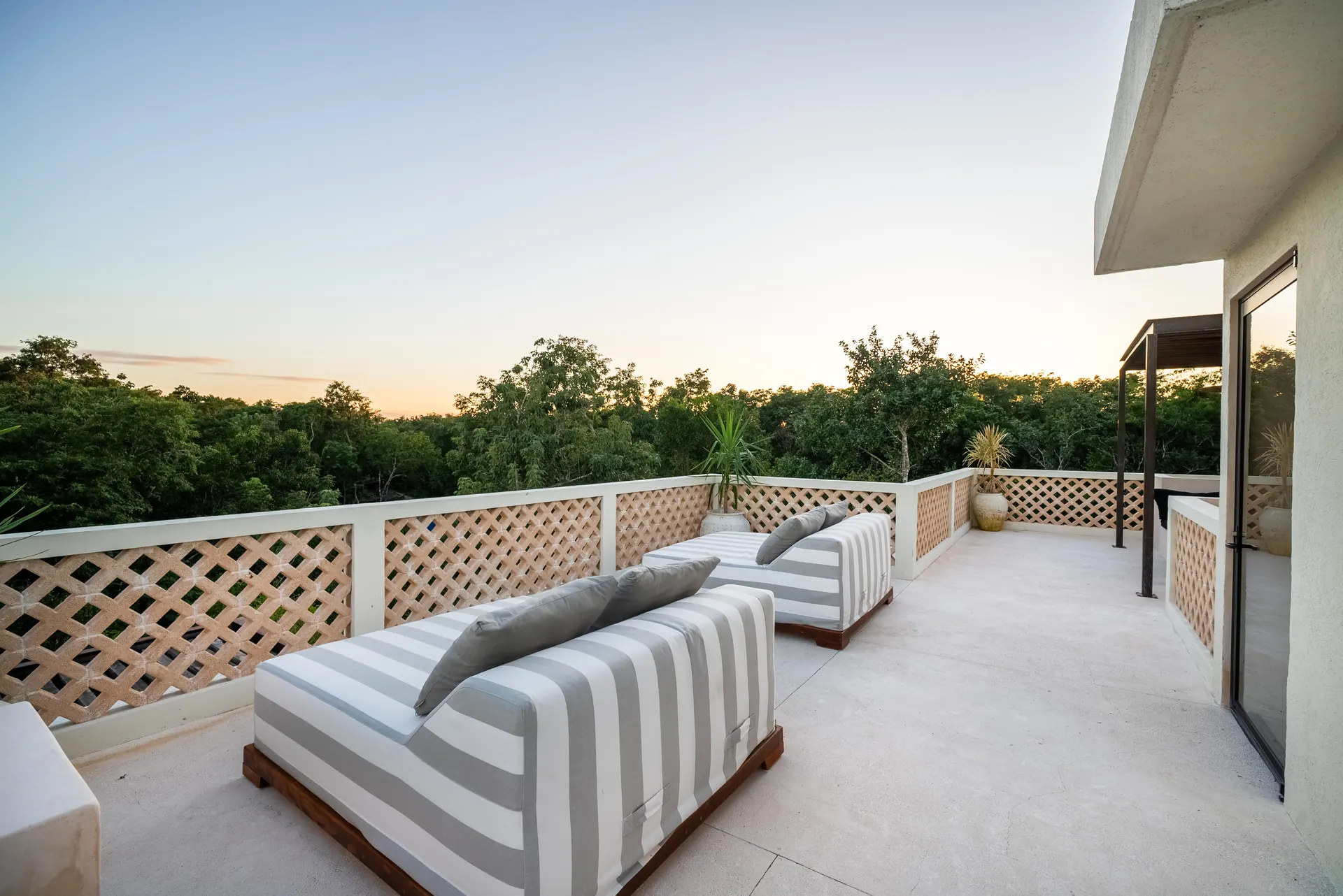 Shaded rooftop lounge looking over the jungle canopy at dusk